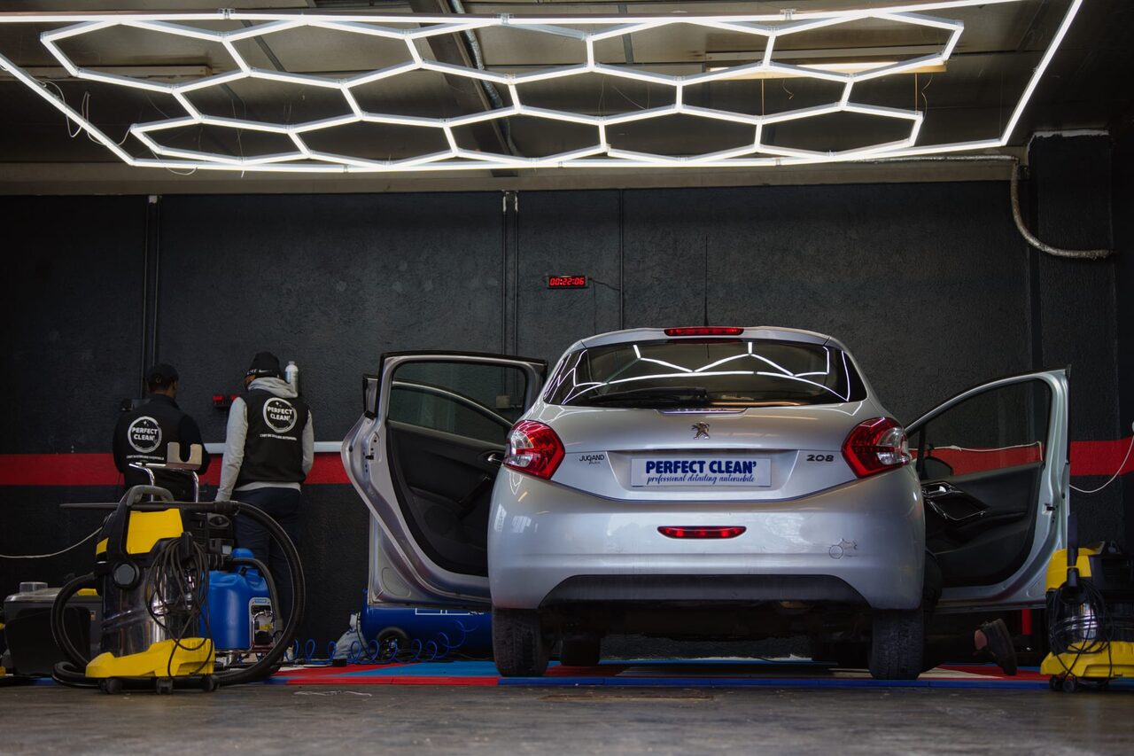 Vue large : deux opérateurs travaillant à l'arrière de la Peugeot 208 sous la rampe LED