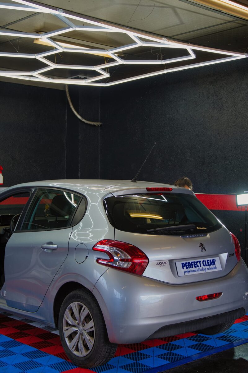 Trois-quarts arrière gauche de la Peugeot 208 sous l'éclairage LED hexagonal de l'atelier
